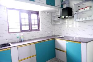 a kitchen with blue and white cabinets and a window at Mulberry STAY in Madikeri