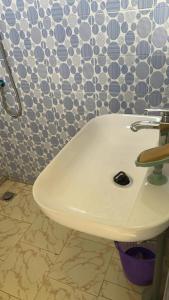 a white sink in a bathroom with a wall at Kitokina Résidence in Saint-Louis