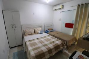 um pequeno quarto com duas camas e uma janela em Suíte Hospedagem Ohana em Penha