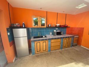 a small kitchen with orange walls and blue tiles at Studio meublé Climatisé indépendant in Ouoran