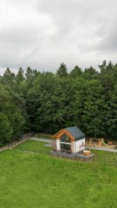 a small building in a field with a playground at Okno na Beskidy-domek LAS z balią , sauną i niesamowitym widokiem na góry in Maków Podhalański