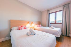 a hotel room with two beds and a window at Ereza Villas Alicia in Caleta De Fuste
