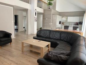 a living room with a black leather couch and a table at Loft apartment für bis zu 4 Personen in Malterdingen