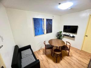 a living room with a table and chairs and a tv at Davao Condo 2BR Pool Wifi Netflix in Davao City