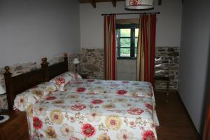 a bedroom with a bed with a floral bedspread at Casa Teillor in Moldes