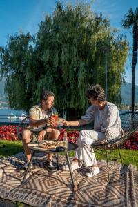 two people sitting at a table in a park at Hotel la Palma au Lac in Locarno