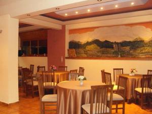 a room with tables and chairs and a painting on the wall at Hotel Aoos in Konitsa
