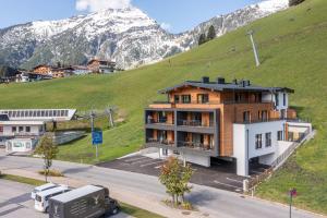 a building on a hill with a mountain in the background at Alpenzauber Apartments by Monteviva in Berwang