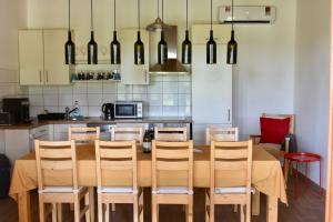 a kitchen with a wooden table with chairs and a kitchen with white cabinets at Kövidinka Vendégház in Izsák