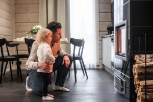 a man and woman sitting on the floor in front of a fireplace at Santa's Luxury Boutique Villa - Santa Claus Village in Rovaniemi