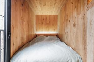 ein Bett in einem kleinen Zimmer mit einer Holzwand in der Unterkunft Bosuil in Retie