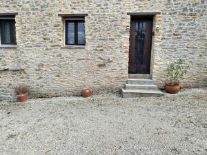 a stone building with a door and stairs and potted plants at Gite Le petit moineau in Corgnac-sur-lʼIsle