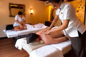 a woman giving a man a massage in a hotel room at STORY Seychelles in Beau Vallon