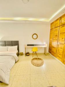 1 dormitorio con cama, escritorio y silla amarilla en Résidence cosy or, en Douala