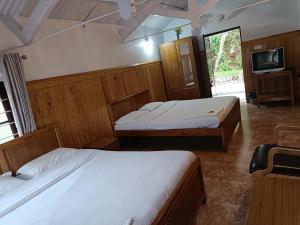 una camera con due letti e una tv di Trilan Cottages - Donnington Road a Kotagiri