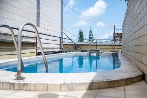 a swimming pool with metal hand rails next to a building at Résidence cosy or in Douala