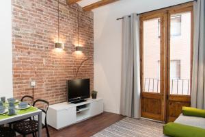 a living room with a brick wall and a tv at Apartments Barcelona Sagrada in Barcelona