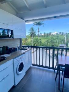cocina con lavadora y balcón en Duplex du Golfeur, en Saint-François