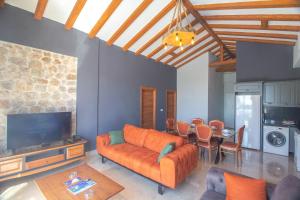 a living room with an orange couch and a table at Tlos Deluxe 3+1 Villa ,Özel Havuzlu, Fethiye in Fethiye
