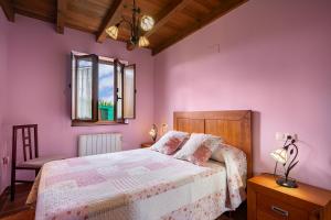 Schlafzimmer mit rosa Wänden, einem Bett und einem Stuhl in der Unterkunft Apto Rosa - Casa el gaitero in Susacasa
