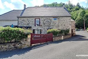 a stone house with a red bench in front of it at La Ferrandaise in Chambon-sur-Lac