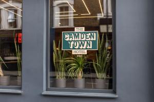 a sign in a window with plants in pots at The Camden Town Hotel in London +27 photos