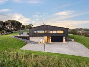 a large black house with a large driveway at Skyfall - Luxury Country Retreat in Waimauku