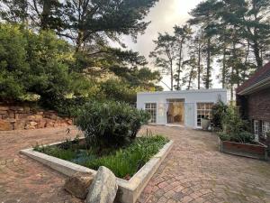 een klein wit huis met een stenen oprit bij Mountain Vineyard Cottage in Kaapstad