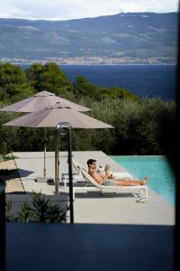 a man laying in a chair next to a pool at Luxusvilla Moana mit Olivenhain in Vrbnik