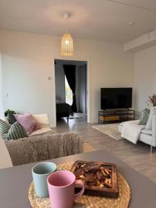 a living room with a couch and a table with cups at Moderni kaksio lähellä keskustaa in Seinäjoki