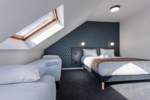 a attic bedroom with two beds and a window at Kyriad Saint Brieuc - Tregueux in Tregueux +28 photos