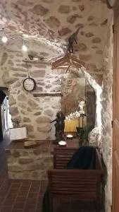 a room with a stone wall with a clock on the wall at La chambre dans la roche in Saint-Martin
