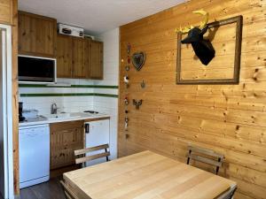 a kitchen with a wooden wall with a table and a sink at Enchanteur 2 pièces pour 4 pers. avec balcon, Alpe d'Huez - proche pistes et centre - FR-1-405-157 in L'Alpe-d'Huez