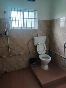 a bathroom with a toilet and a window at Greenwood Cabins Homestay, The Greenhouse in Jorhāt