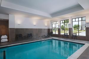 a pool in a hotel with chairs and a table at Courtyard by Marriott Dallas Frisco in Frisco