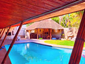 a house with a swimming pool with a thatch roof at Budget Haven Durbanville in Cape Town