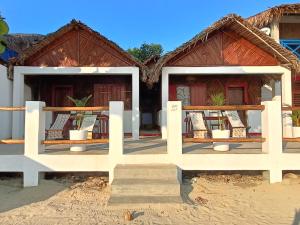 een huis op het strand met tafels en stoelen bij CHEZ ALEX in Nosy Be