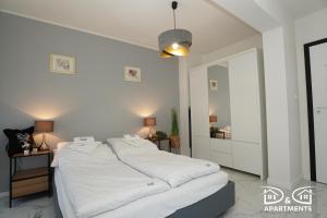 - une chambre blanche avec 2 lits et un miroir dans l'établissement Pine Tree House 6 D&D Apartments, à Międzywodzie