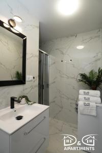 une salle de bain blanche avec un lavabo et un miroir dans l'établissement Pine Tree House 6 D&D Apartments, à Międzywodzie