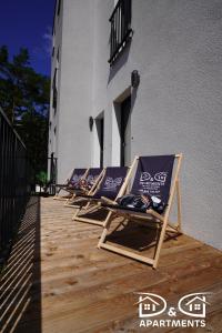 une rangée de chaises longues assises sur une terrasse à l'extérieur d'un bâtiment dans l'établissement Pine Tree House 6 D&D Apartments, à Międzywodzie