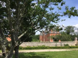 a large brick building behind a wall and a tree at Gîte grande famille Alisiers in Lailly-en-Val