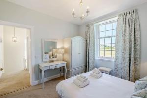 a bedroom with two beds and a desk and a window at Coulter Cottage in Earlsferry
