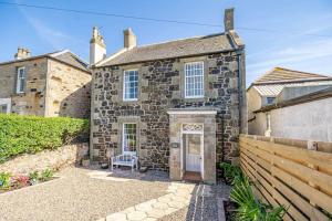 an old stone house with a white door at Coulter Cottage in Earlsferry