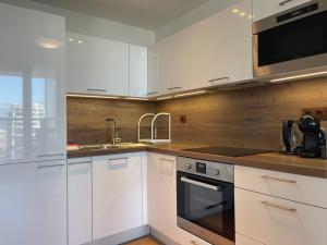 une cuisine avec des armoires blanches, un évier et un micro-ondes dans l'établissement SAG 28 floor Panrama city free parking free wifi, à Bratislava 10 autres photos