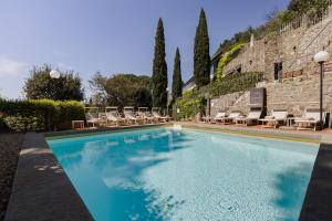 ein Swimmingpool mit Liegestühlen und einer Mauer in der Unterkunft FH55 Hotel Villa Fiesole in Fiesole