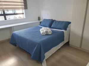 una camera da letto con un letto blu con asciugamani sopra di Flat com Ar, SmarTV43, wifi, estac, novo, Selenita2 a Barueri