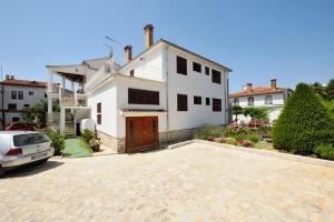 a white house with a car parked in a driveway at Guest House AB Adria Home in Rovinj