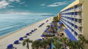 a beach with blue umbrellas and chairs and the ocean at DoubleTree Beach Resort by Hilton Tampa Bay – North Redington Beach in St Pete Beach