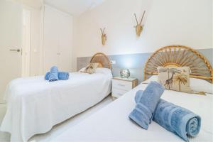 two beds in a bedroom with white walls and blue towels at Ático Balinés con vistas al mar in Canet de Berenguer