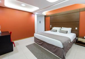 a bedroom with a large bed with an orange wall at Centromar Hotel in Balneário Camboriú